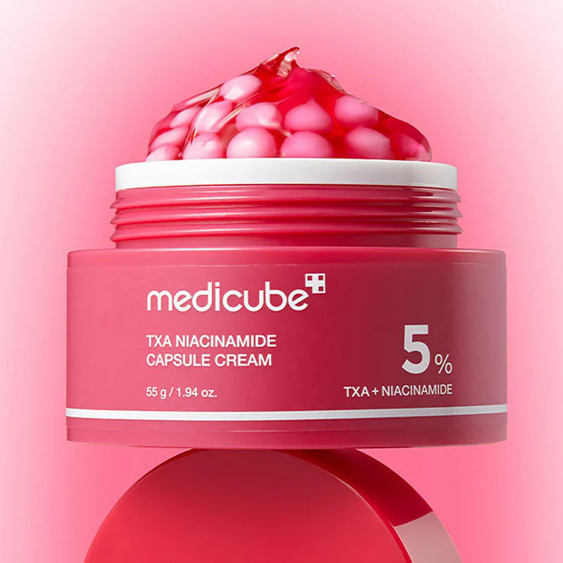 Boião do TXA Niacinamide Capsule Cream aberto sobre fundo gradiente cor-de-rosa