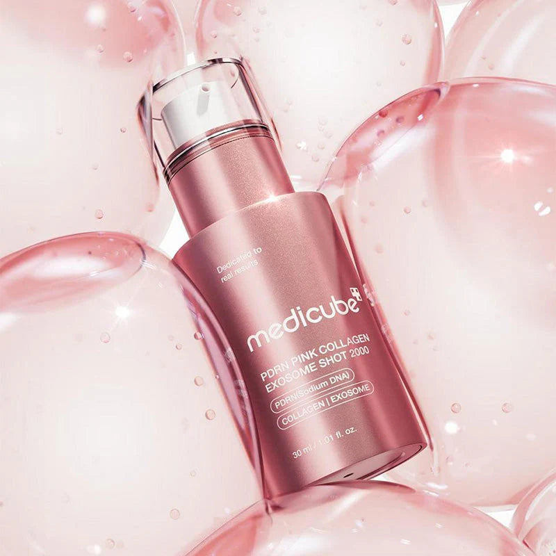 Frasco do sérum PDRN Medicube deitado entre esferas translúcidas cor-de-rosa