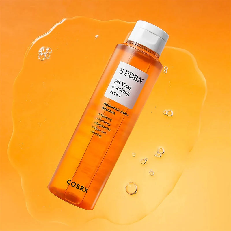 Frasco COSRX 5 PDRN B5 sobre superfície com respingos do tónico cor de laranja