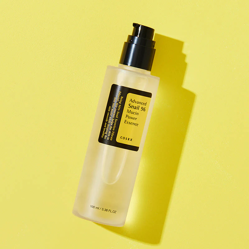 Frasco da COSRX Advanced Snail 96 Mucin Power Essence sobre fundo amarelo dourado