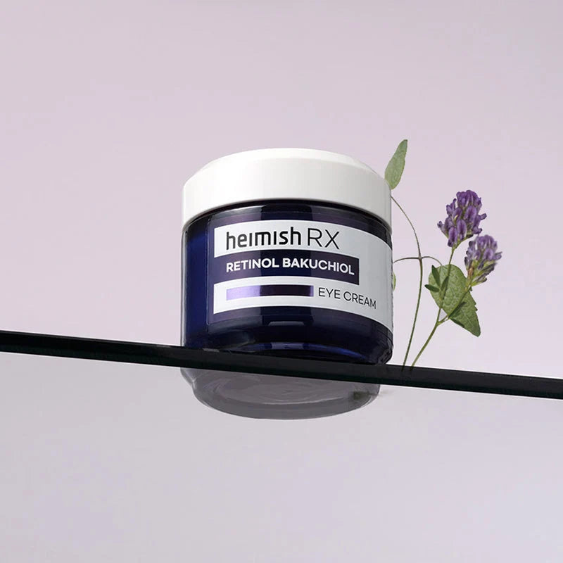 Frasco Heimish RX Retinol Bakuchiol Eye Cream sobre placa de vidro, com flores de lavanda