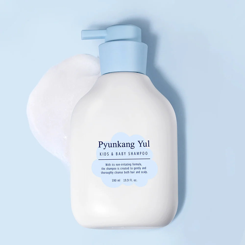Frasco com doseador do champô Pyunkang Yul sobre fundo azul, junto a espuma branca