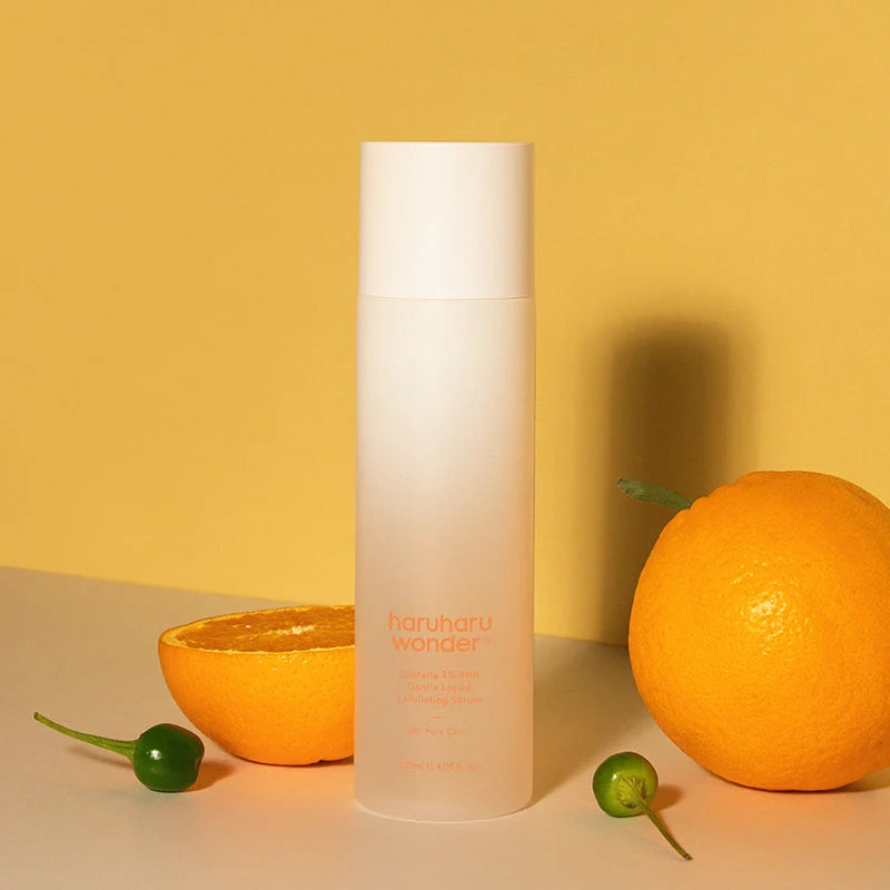 Frasco haruharu wonder Centella 3% PHA entre laranjas e kumquats, fundo amarelo