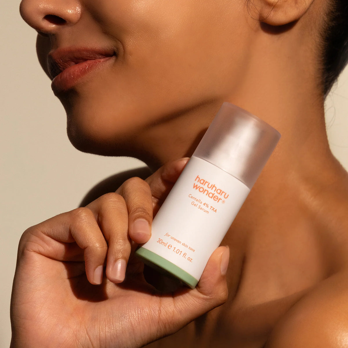 Frasco do sérum Haruharu Wonder Centella TXA segurado junto ao rosto, luz natural
