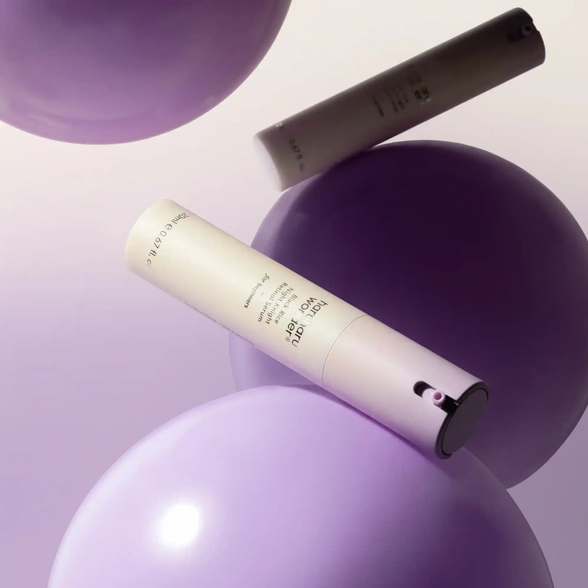 Dois frascos do Haruharu Wonder Black Rice Night Knight Retinol Serum entre esferas lilás