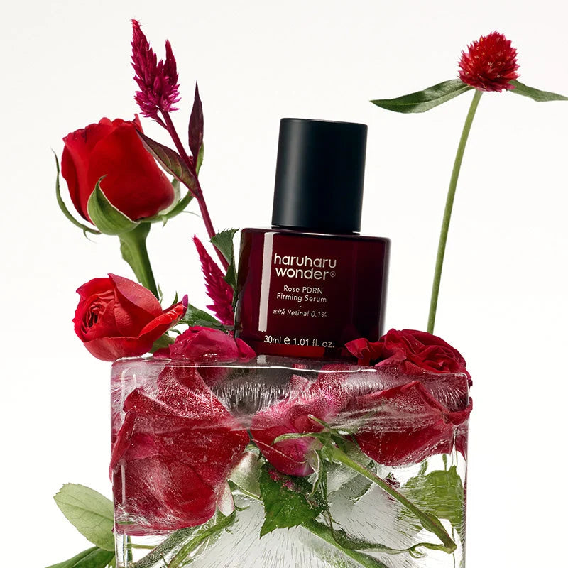 Rose PDRN Firming Serum da Haruharu Wonder colocado sobre rosas congeladas num bloco de vidro