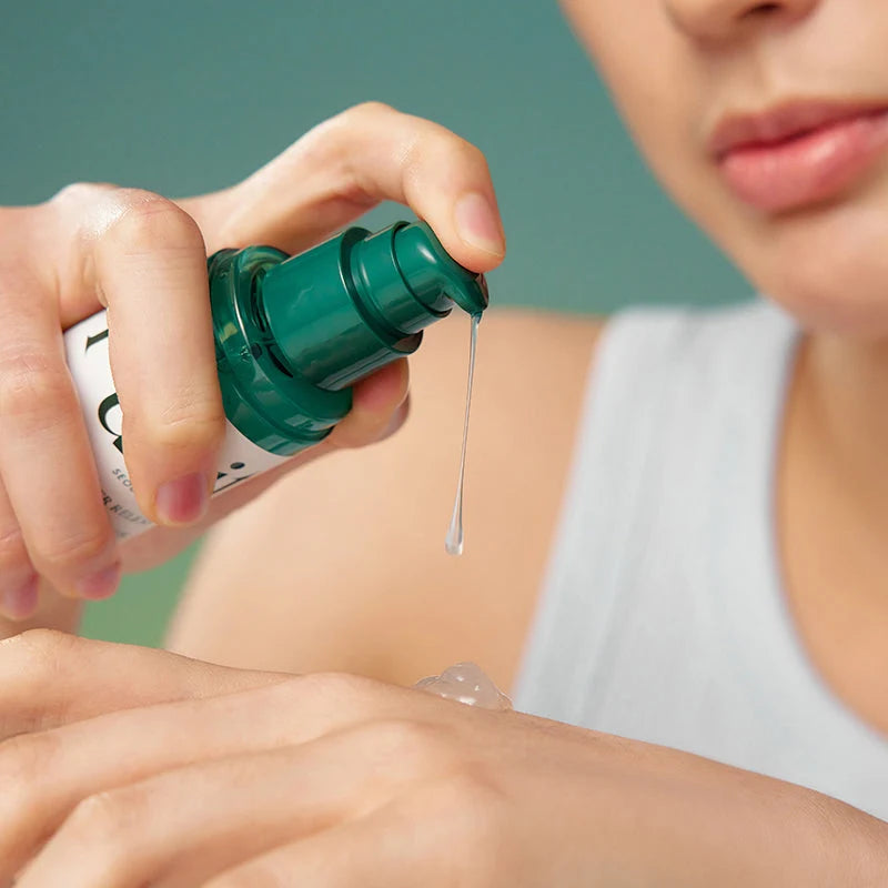 Mão a pressionar a bomba do frasco, com uma gota de gel transparente a cair sobre a outra mão