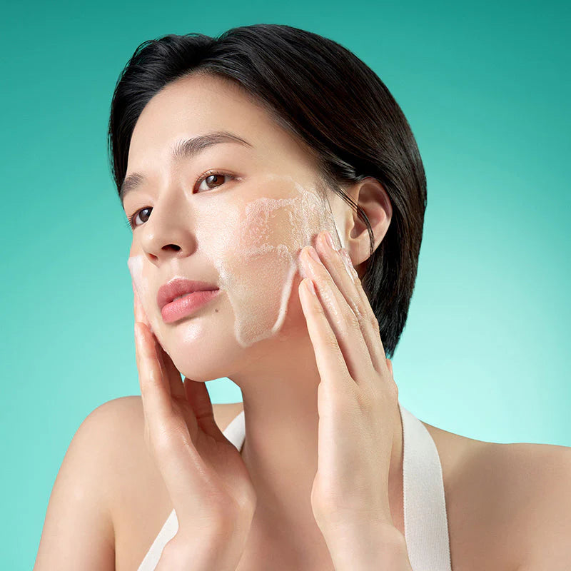 Aplicação espuma do Purito Seoul Mighty Bamboo Panthenol Cleanser no rosto em movimentos suaves