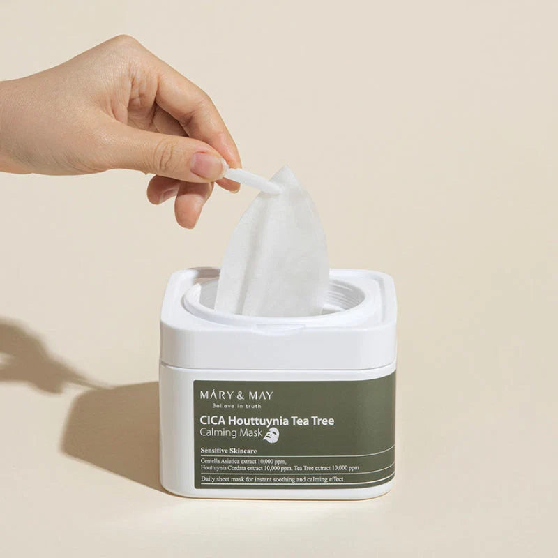 Mão a retirar uma folha da máscara Cica Houttuynia Tea Tree da Mary&May