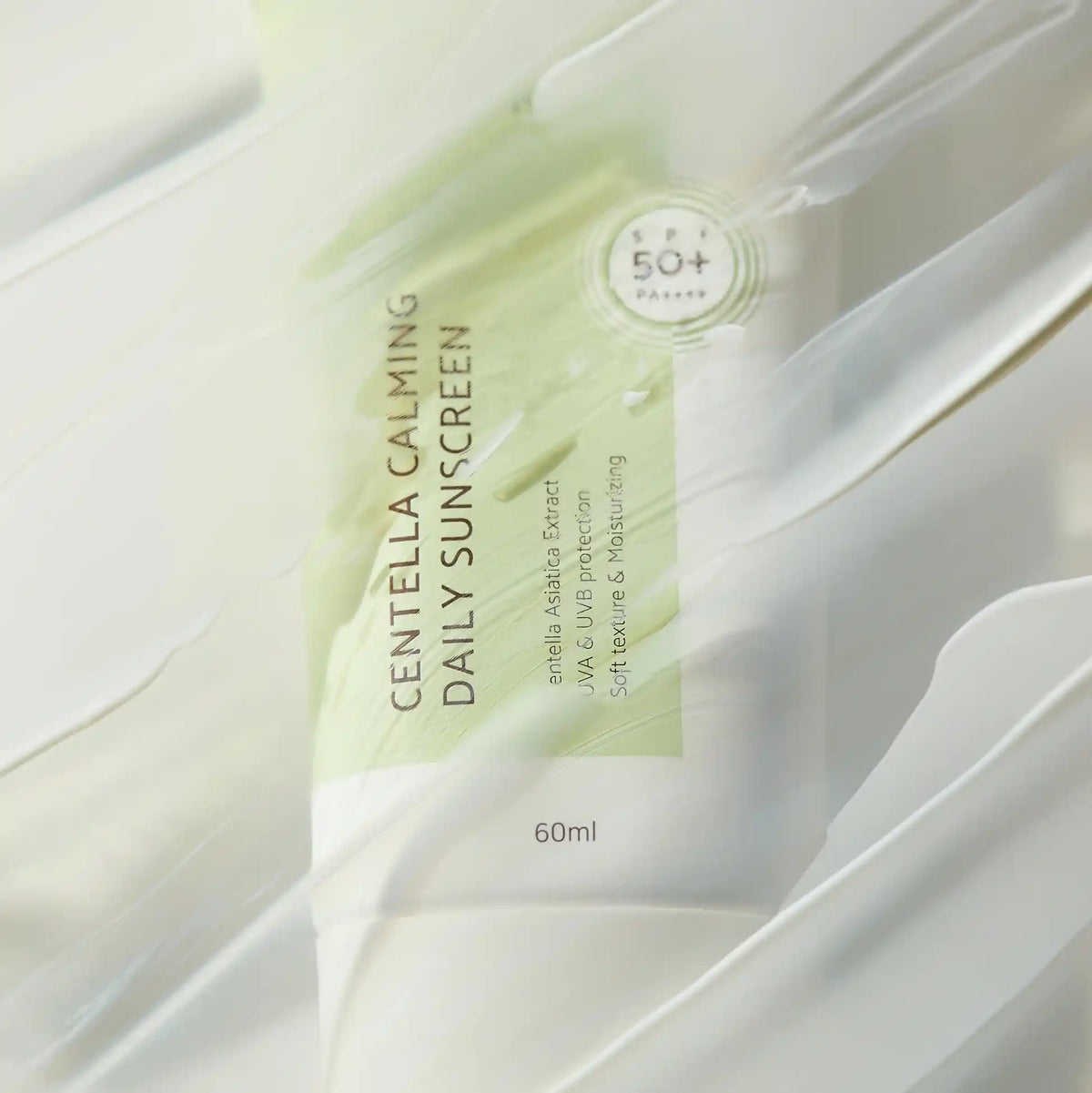 Close-up desfocado da embalagem IUNIK Centella Calming Daily Sunscreen em efeito de movimento suave