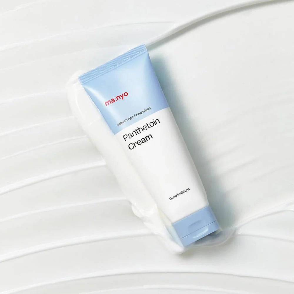 Tubo do ma:nyo Panthetoin Cream deitado sobre fundo com creme espalhado