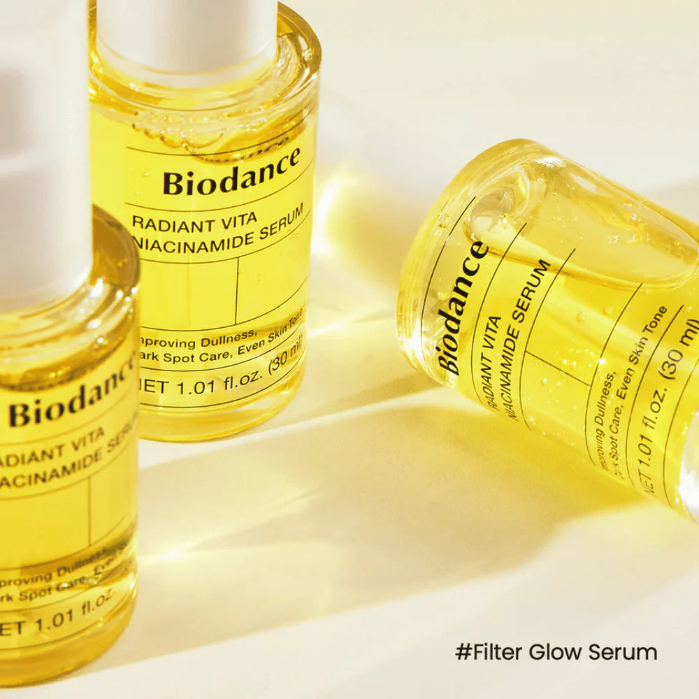 Biodance Radiant Vita Niacinamide Serum frasco transparente com sérum dourado deitado e em pé