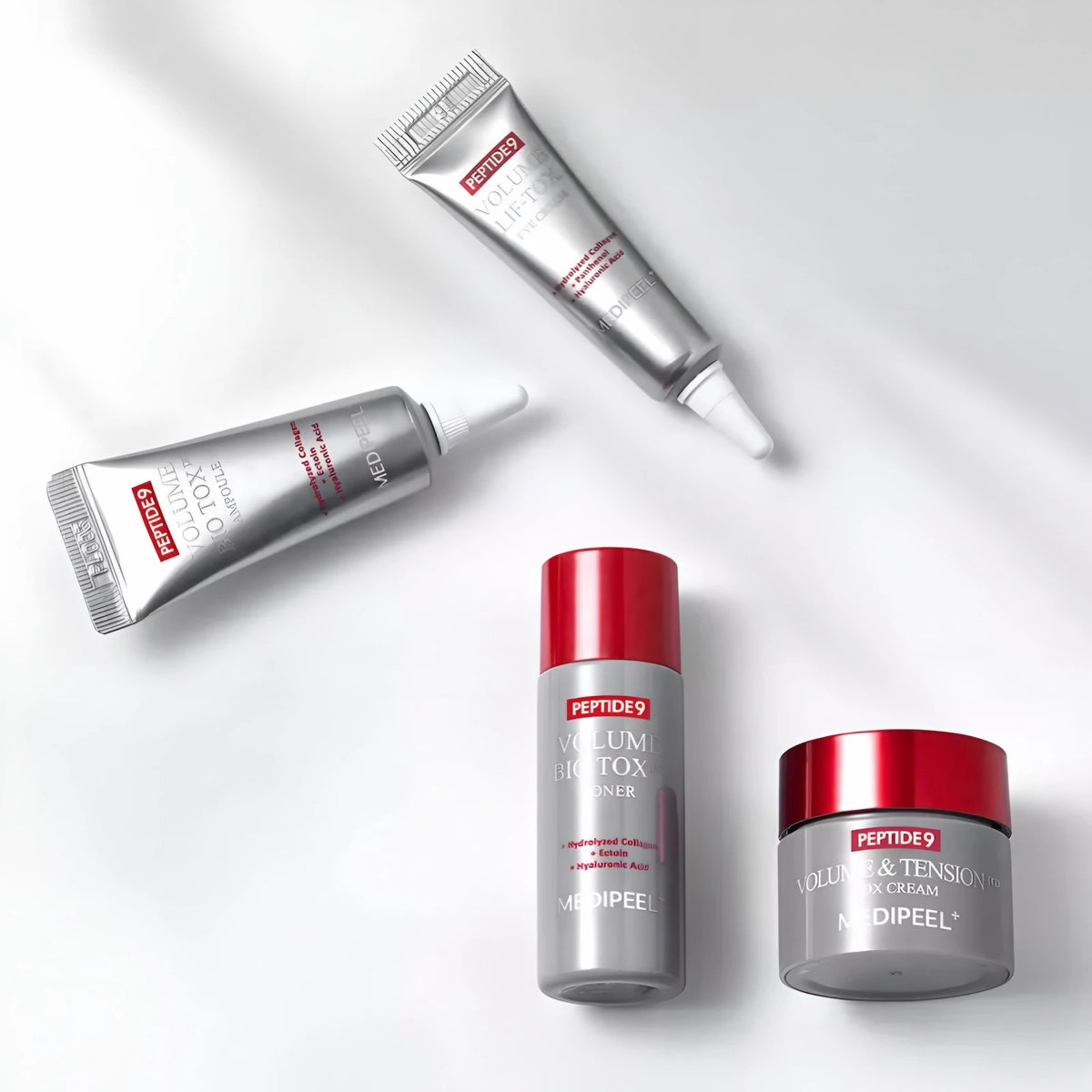 Tónico, ampola, creme de olhos e creme do kit dispostos sobre fundo branco com sombras suaves