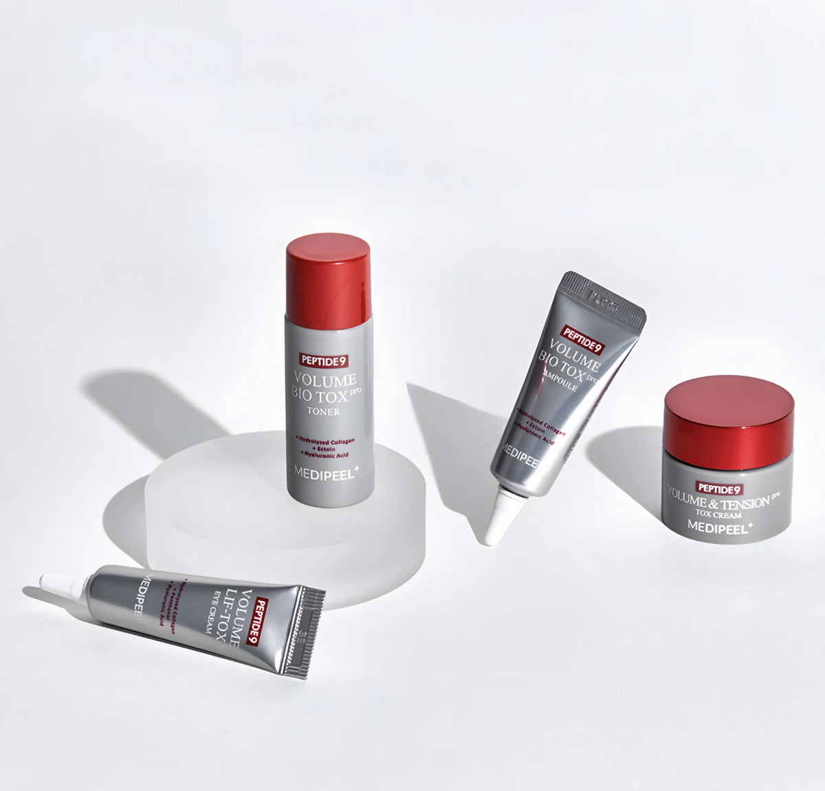 Tónico sobre pódio branco, com a ampola, o creme e o creme de olhos dispostos à volta