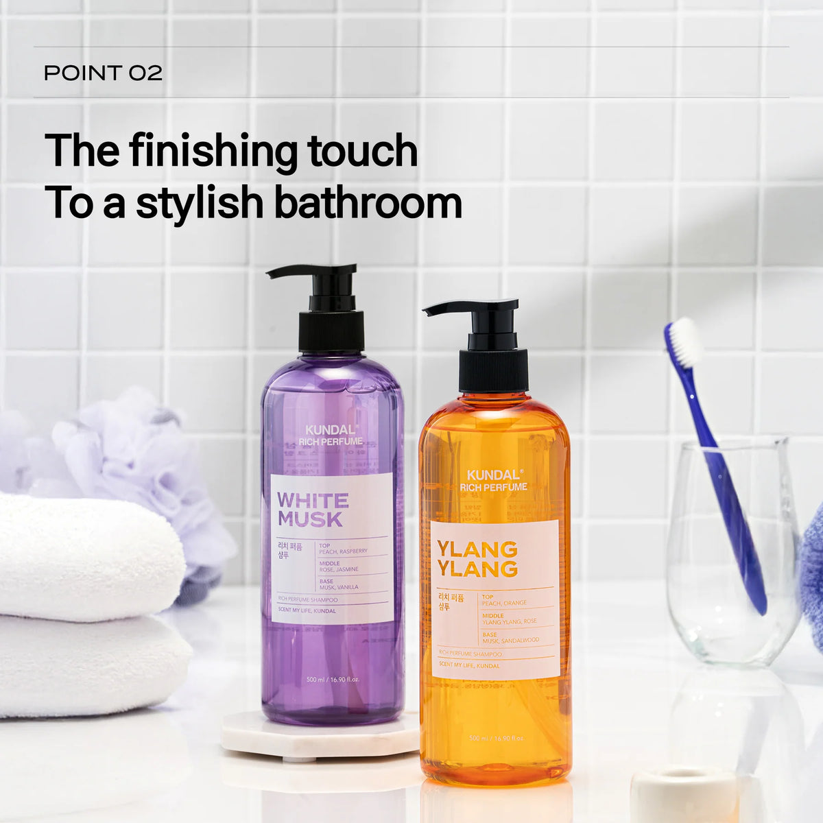 Dois frascos de champô com doseador, um roxo e outro laranja, junto a toalhas numa casa de banho de azulejo branco