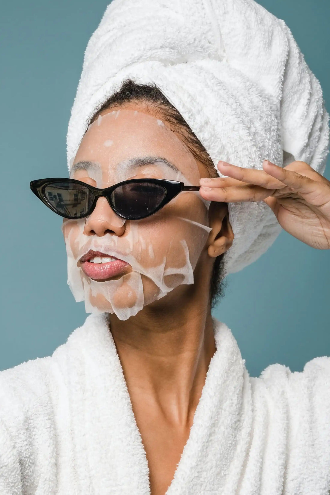 Mulher com máscara facial em folha, toalha na cabeça e óculos de sol — categoria de máscaras faciais